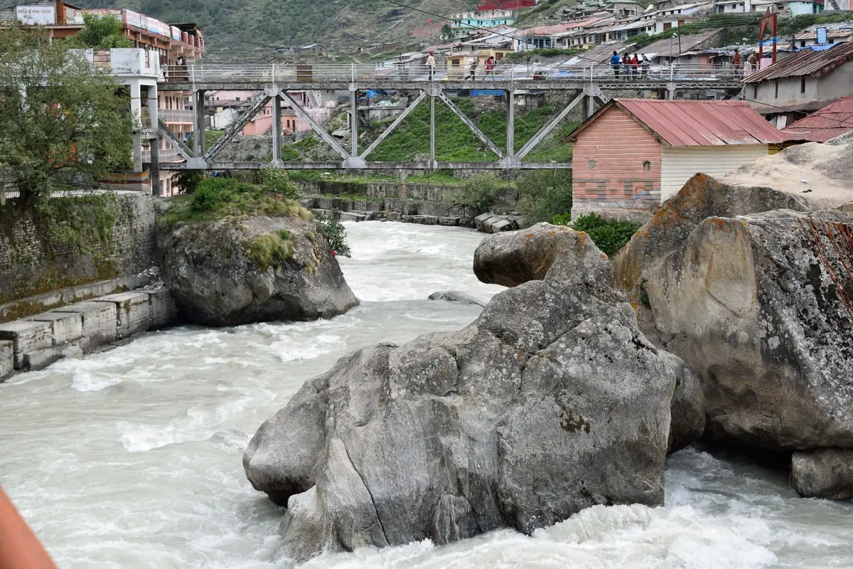 Alaknanda River rushing over large rocks beside the buildings of Badrinath