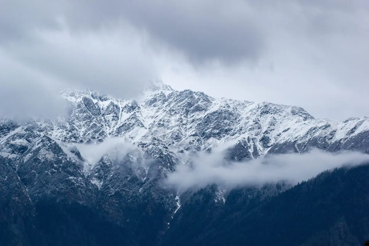 Snow-covered mountain range seen from Auli with clouds in the valleys