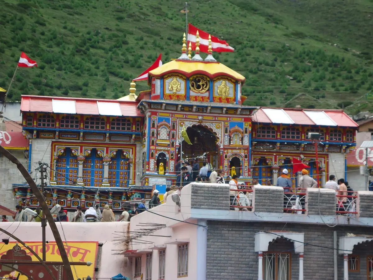 Badrinath Temple with flags on the roof and houses of the town around it