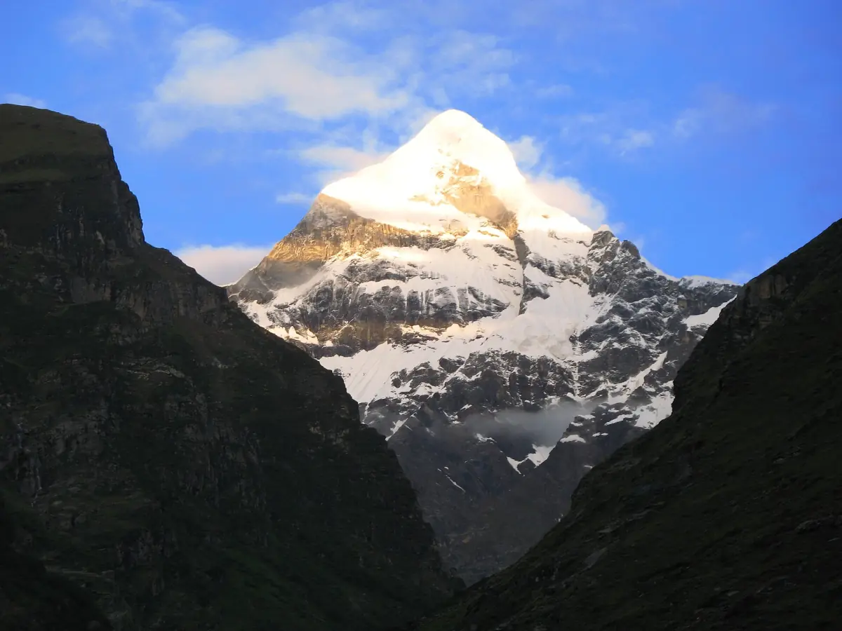 Snow-covered summit of Neelkanth peak seen between two dark valley walls