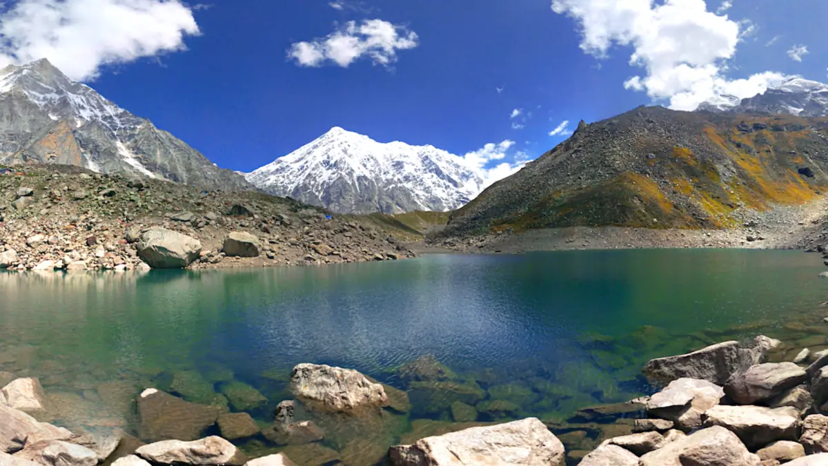 Turquoise Satopanth Lake with a snow-covered peak behind it