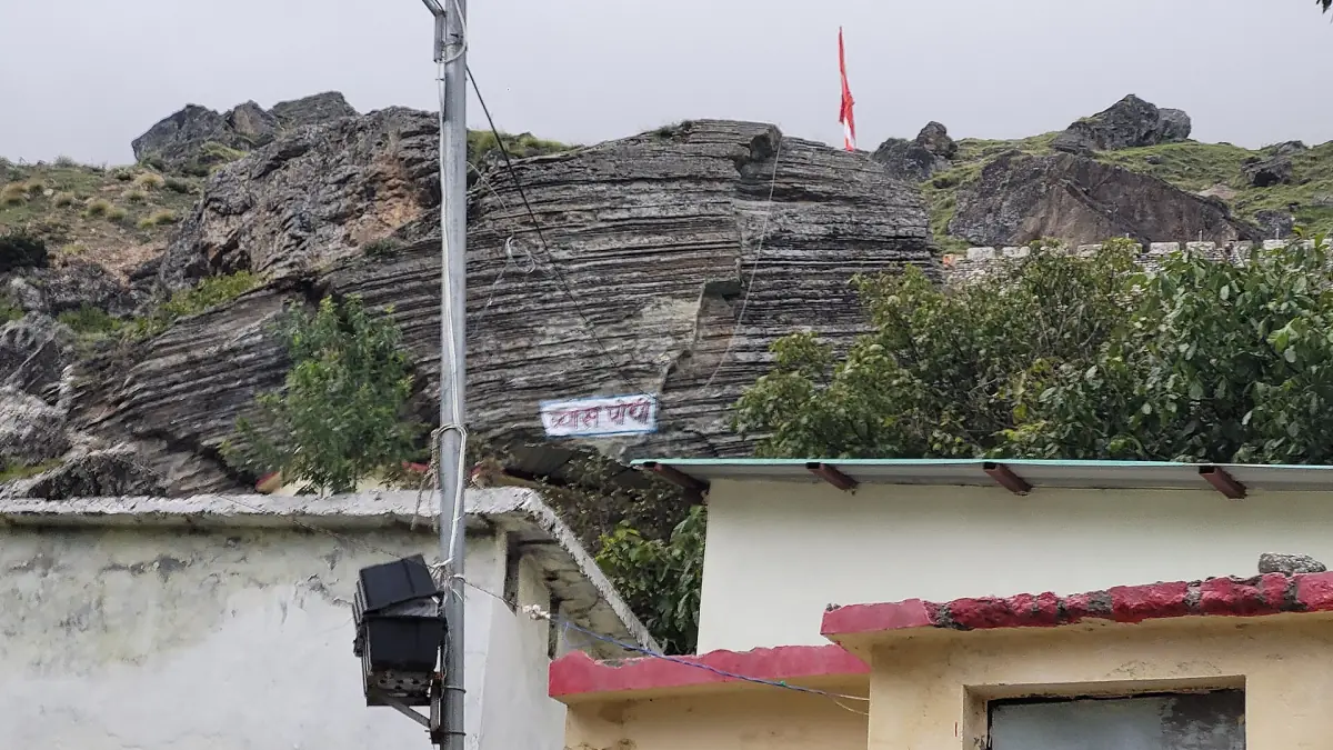 Layered rock face above the cave entrance building near Mana
